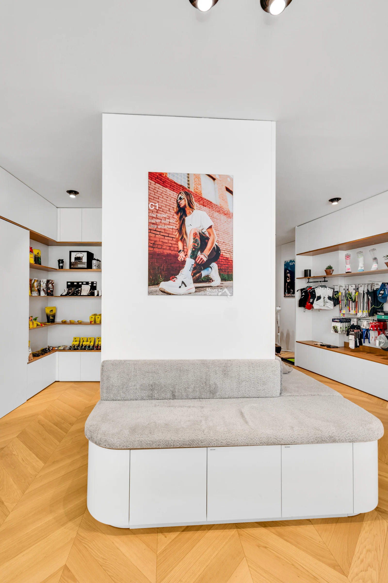 Une banquette grise et des rangements blancs entourent le pilier central du magasin.
