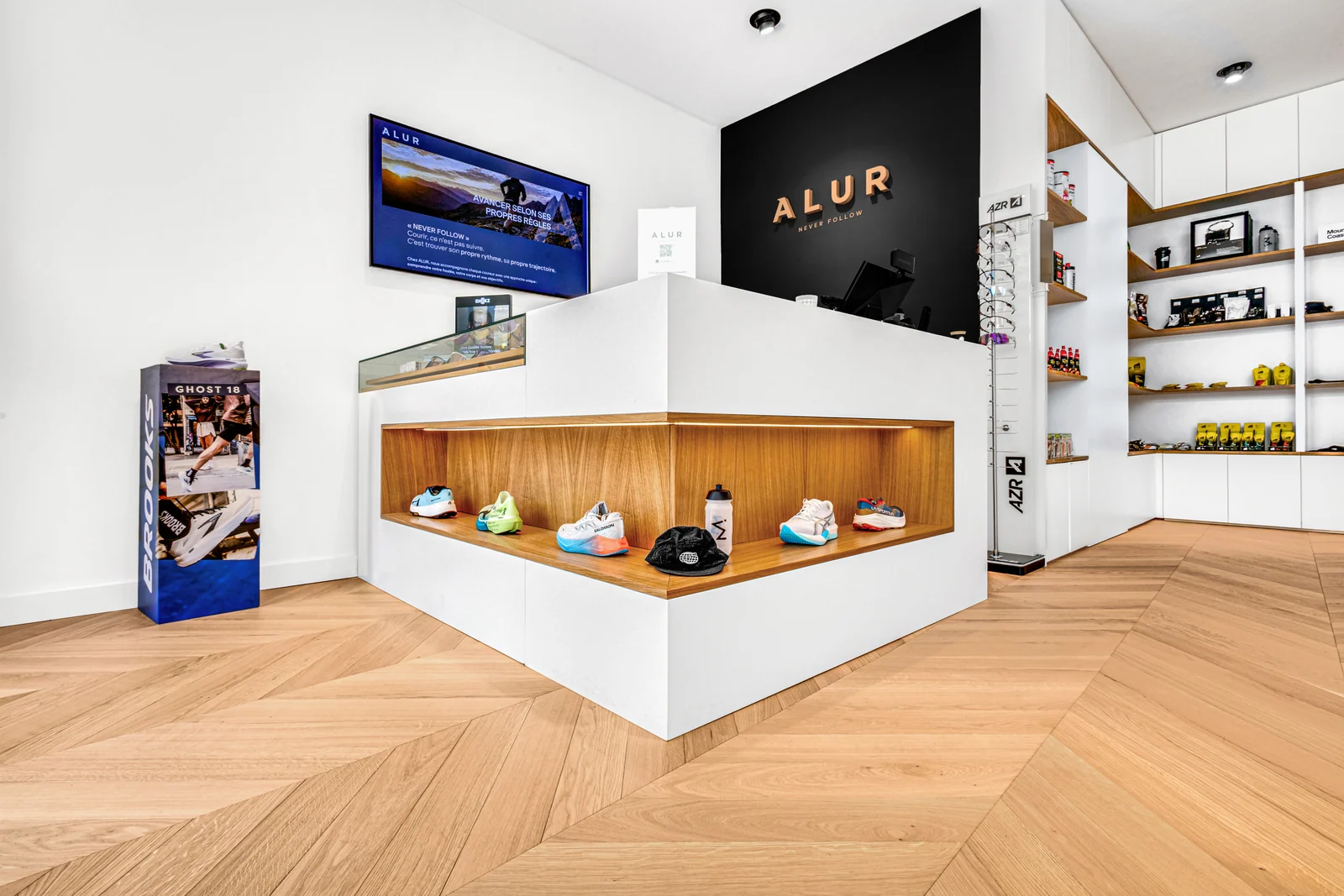 Le comptoir blanc intègre une niche de présentation en bois, devant le mur noir marqué Alur.
