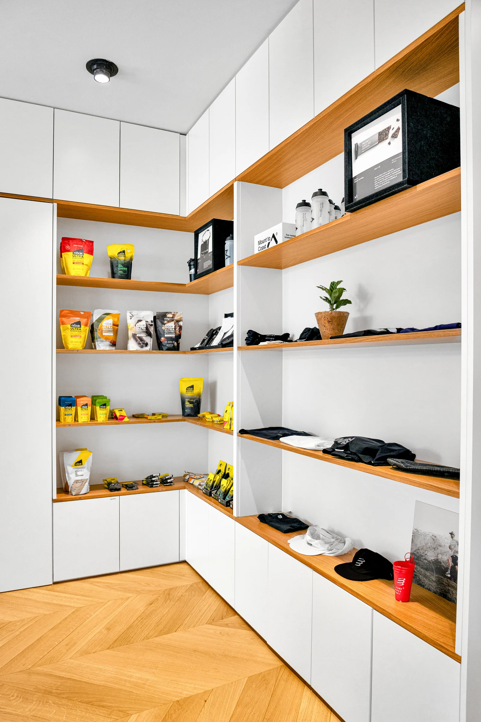 Des tablettes en bois et des niches éclairées présentent les accessoires au-dessus des placards blancs.