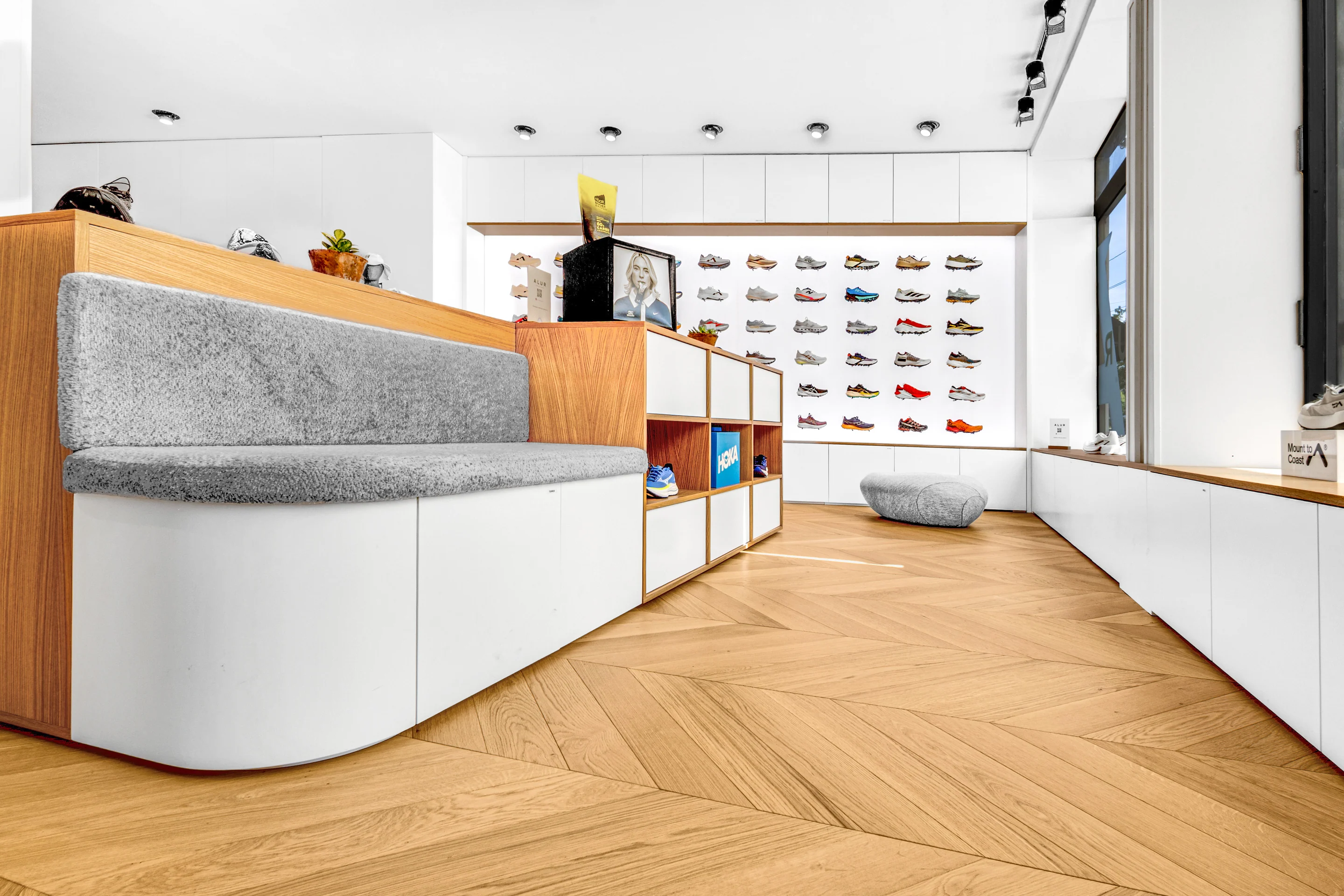 Vue du magasin Alur à Carouge : banquette arrondie, rangements et mur de chaussures rétroéclairé.
