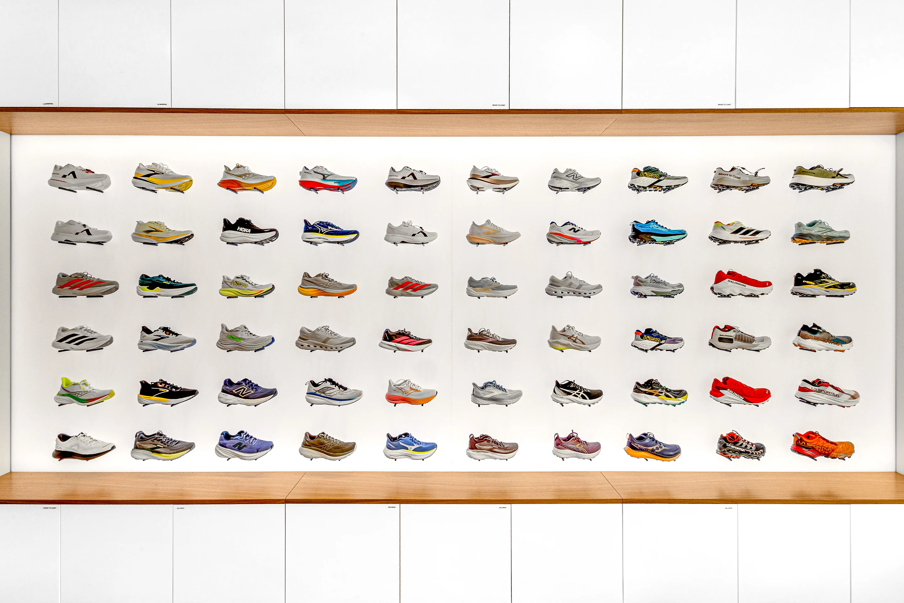 Vue de face du mur de chaussures, encadré de bois et de rangements blancs.