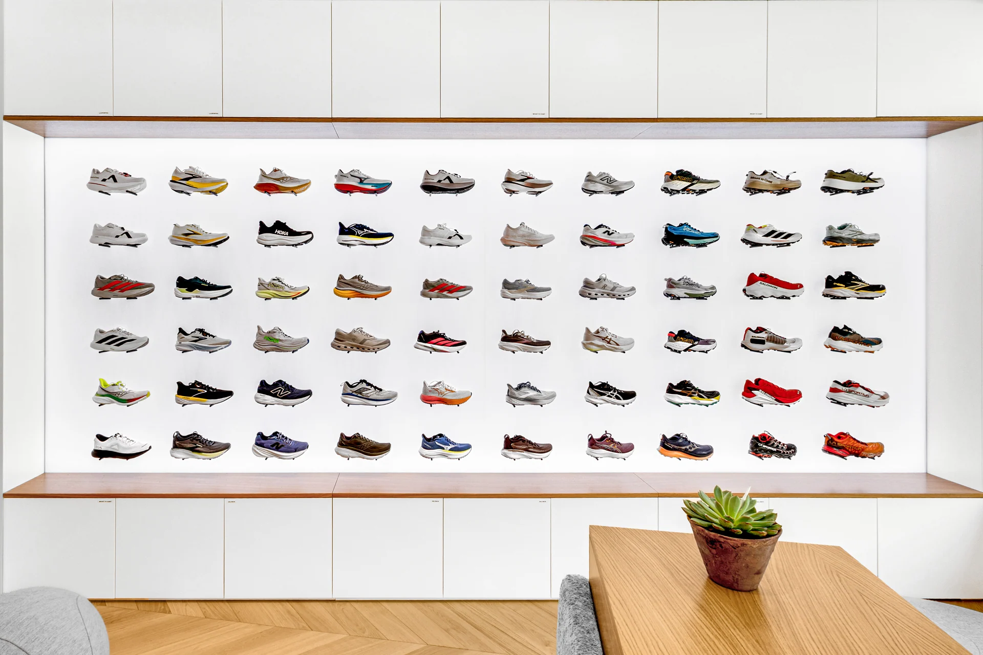 Le mur rétroéclairé présente les chaussures entre deux lignes de rangements blancs.