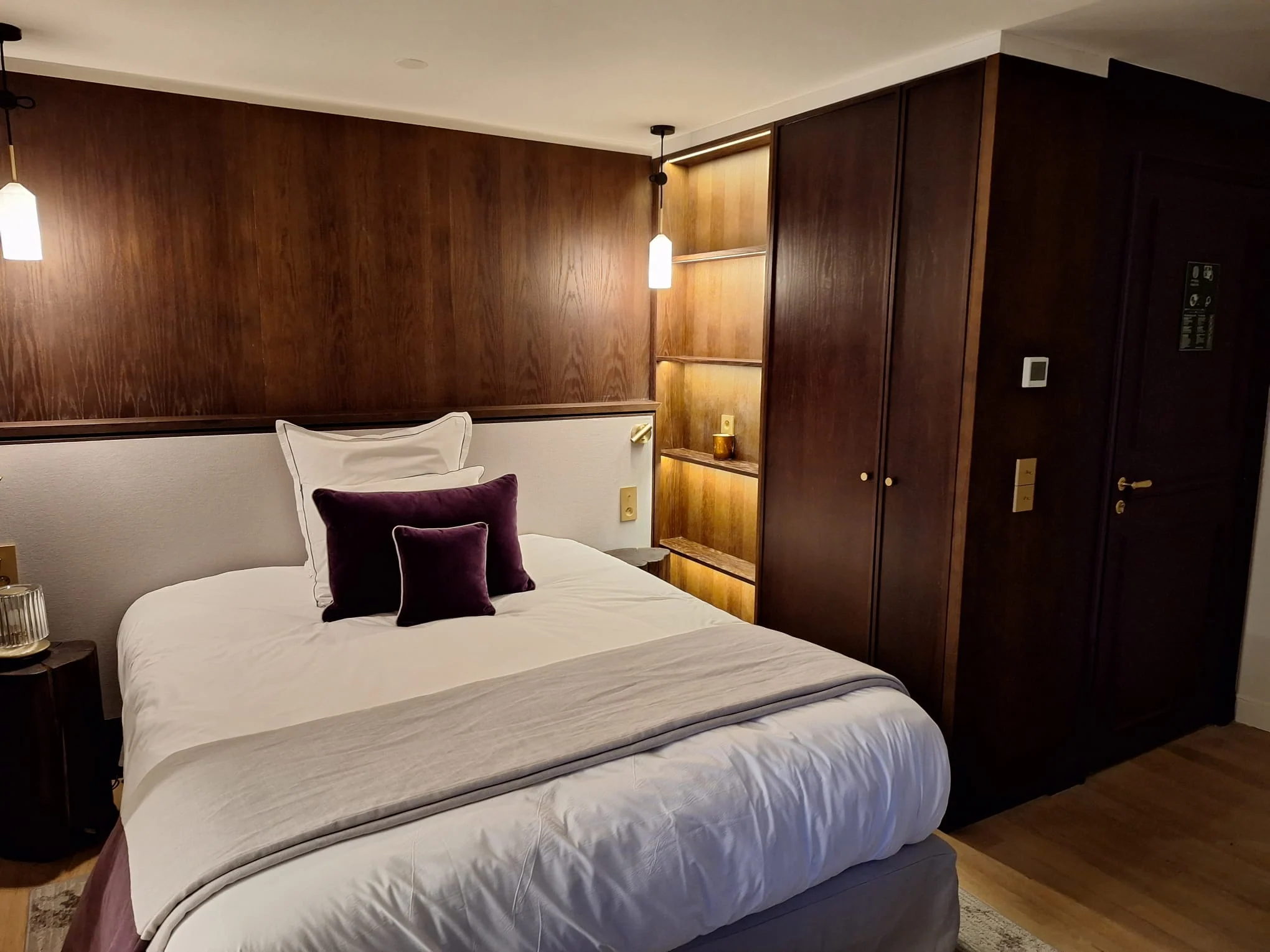 Tête de lit et rangements intégrés en bois foncé.