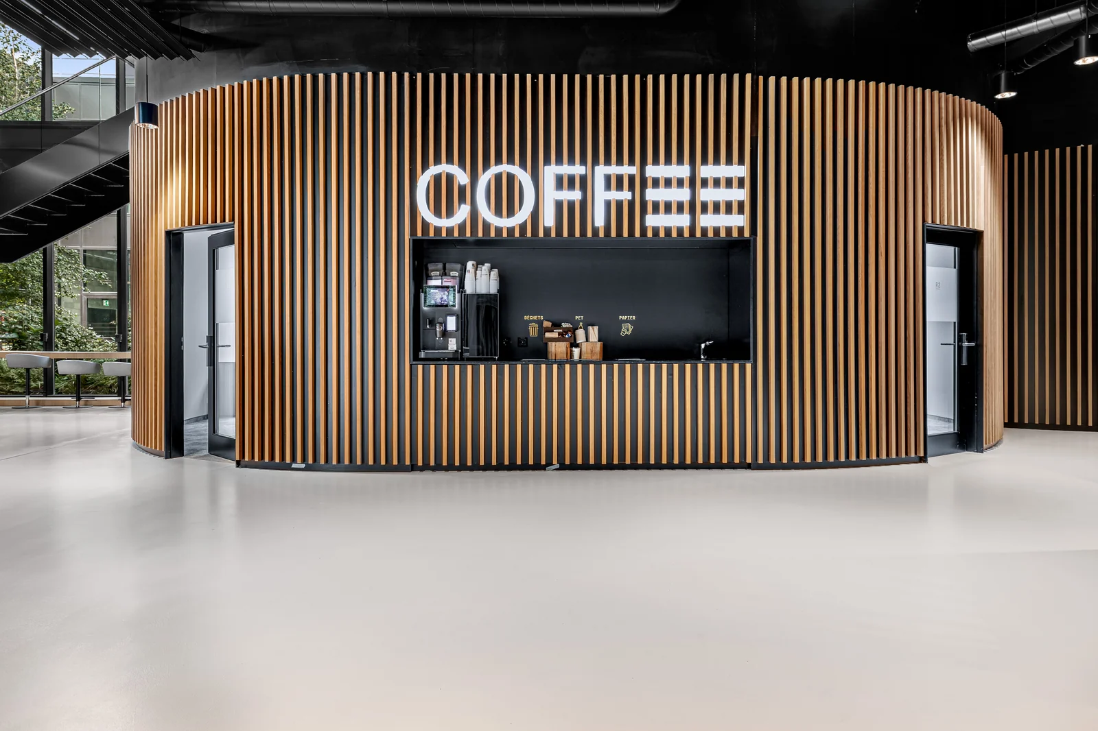 Le coin café est intégré dans un volume arrondi habillé de lames verticales.