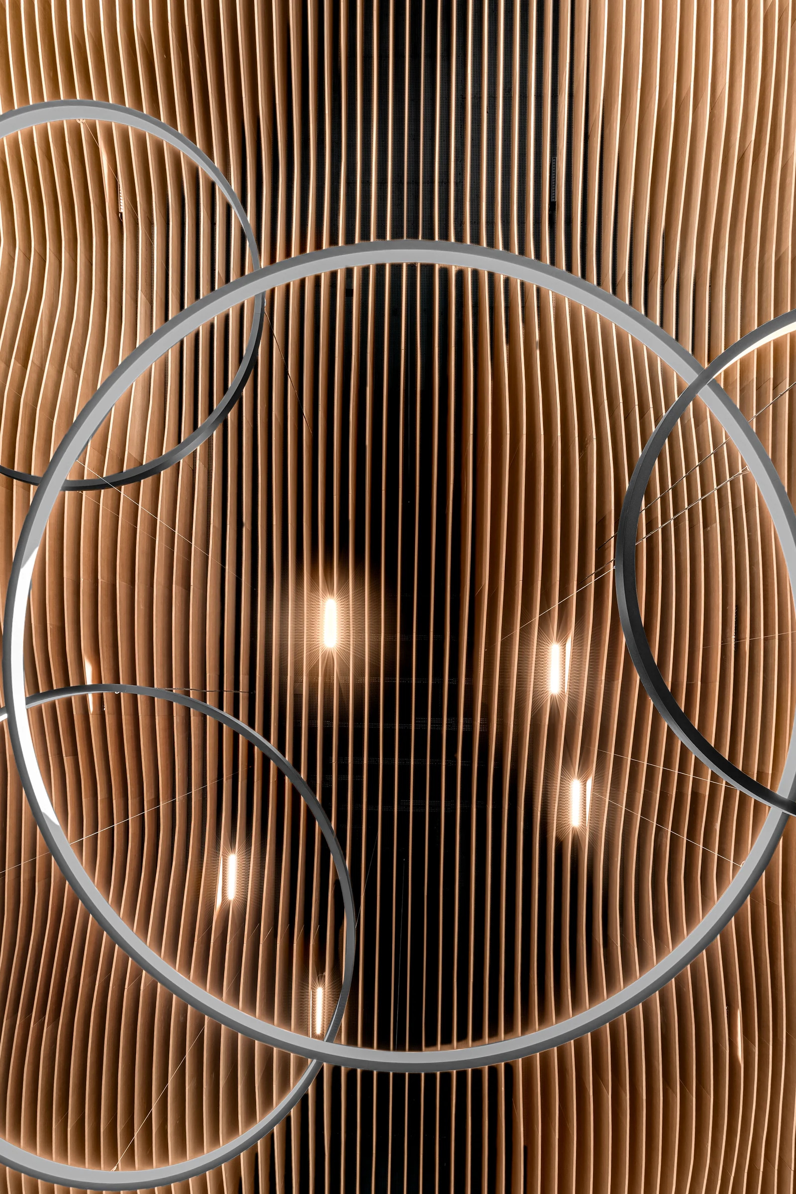 Une suspension circulaire se détache devant le plafond en lames de bois.