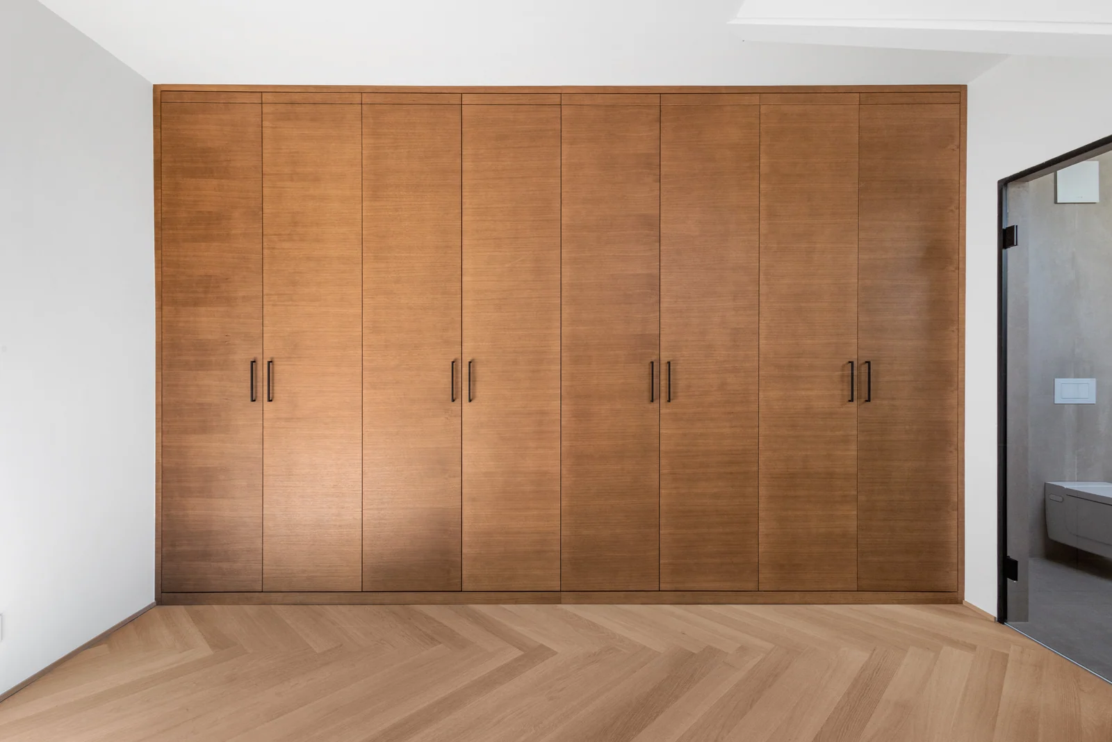 Dressing en bois aux portes fermées, réalisé par IAKO dans un appartement à Nyon