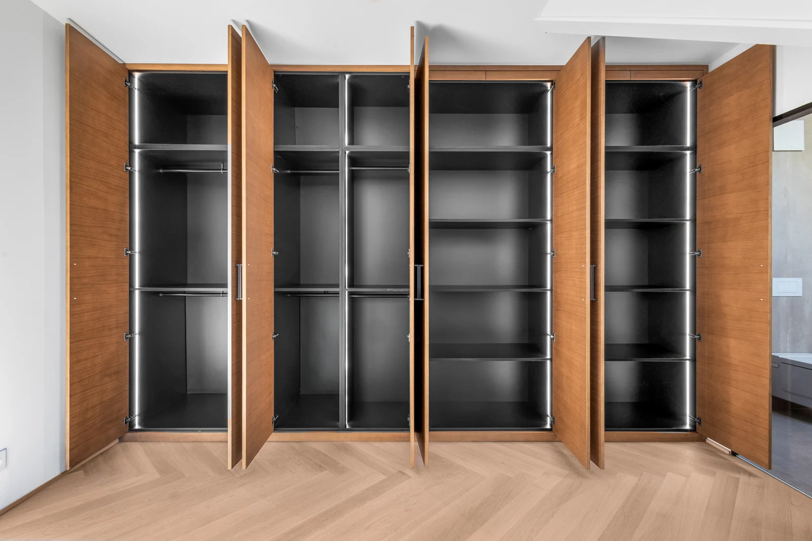 Dressing IAKO à Nyon, portes en bois ouvertes sur les penderies et les étagères
