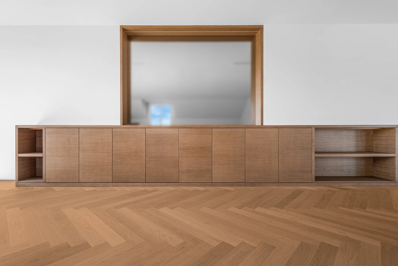 Meuble bas en bois avec portes et niches ouvertes, réalisé par IAKO dans un appartement à Nyon