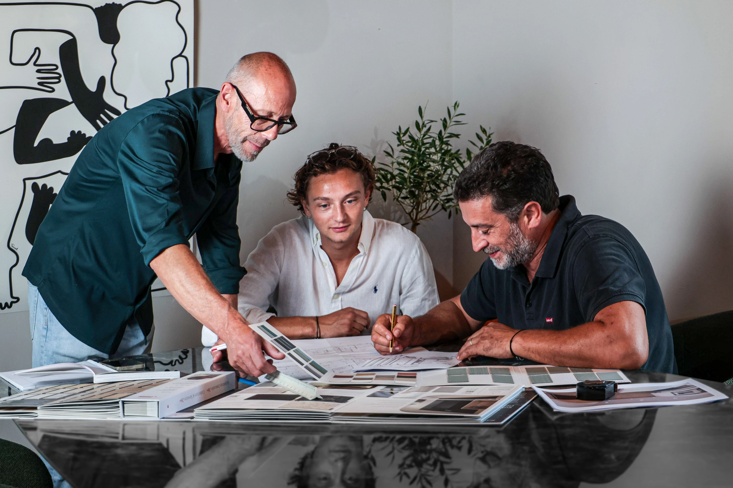Les trois membres de l’équipe IAKO étudient des plans et des échantillons autour d’une table
